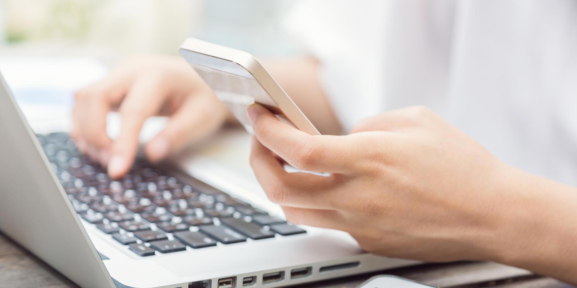 Person sitting at a computer and holding a phone